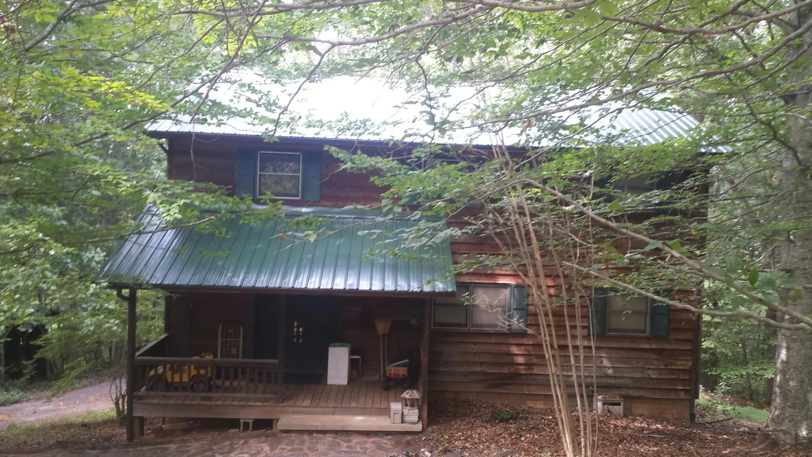 Green metal roof and covered porch on a log cabin in Lansing