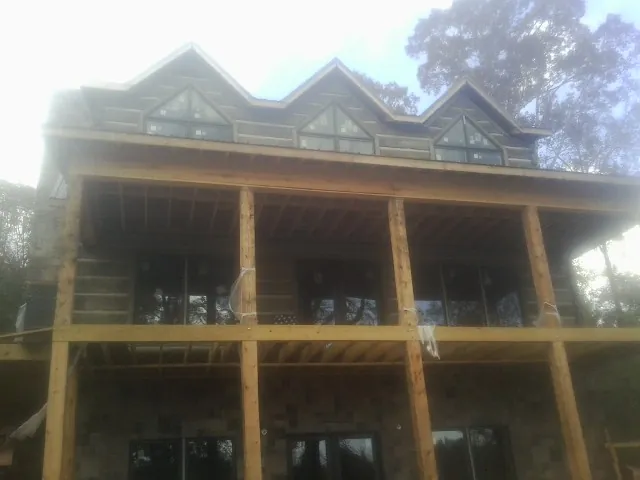Dormers and porch framing on a large log home under construction — Roof Coating work by our crew in Lansing